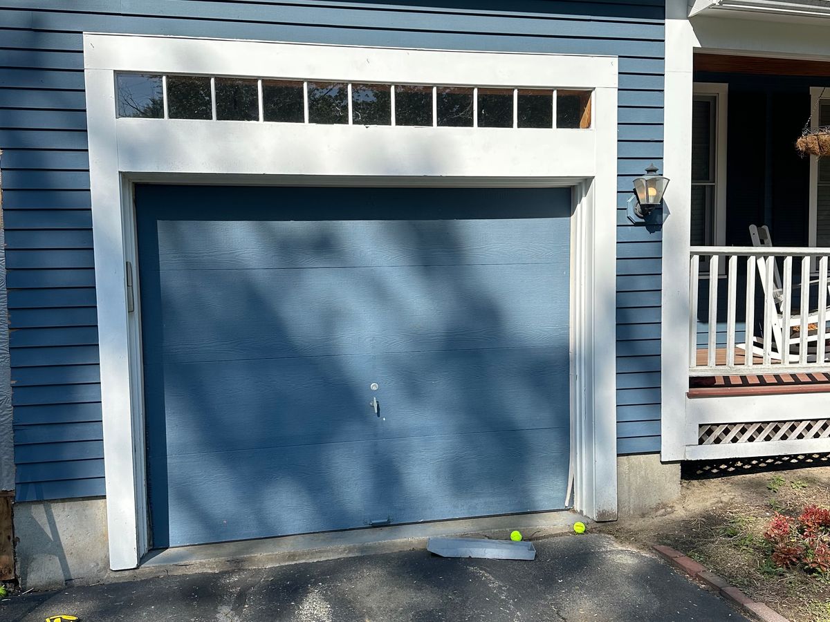 Blue garage door installation in progress on colonial home